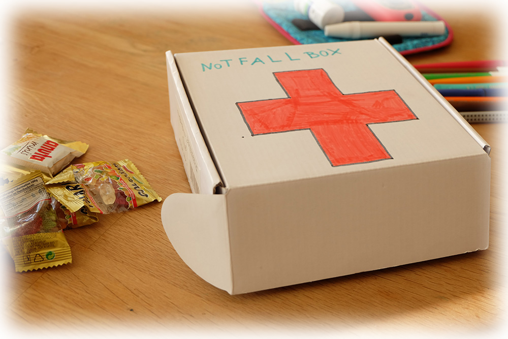 Die Notfallbox sollte am besten als solche gekennzeichnet werden. Die  Lehrer/Erzieher und Mitschüler sollten über die Notfallbox informiert  werden. Die Notfallbox meiner Tochter befindet sich in der Schule direkt  unter ihrem Pult.